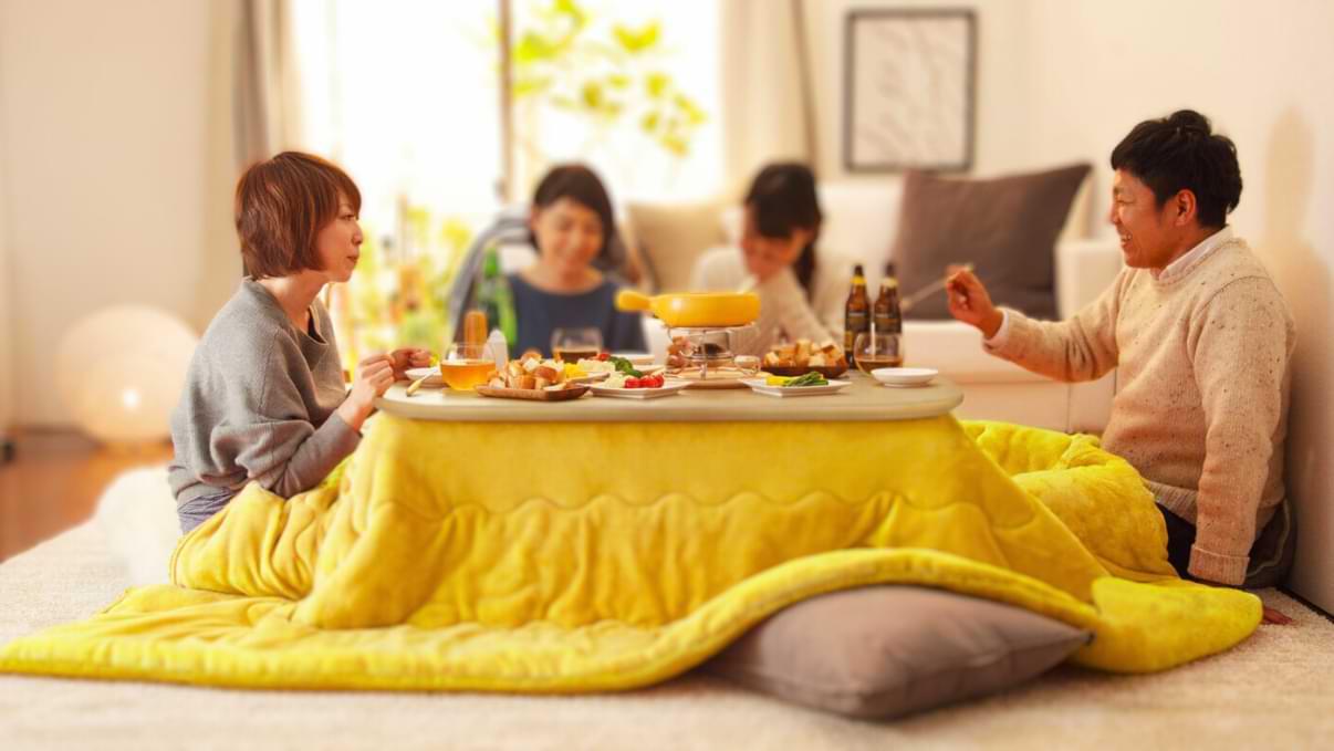 Une famille mange autour d'une table avec la technique du Kotatsu
